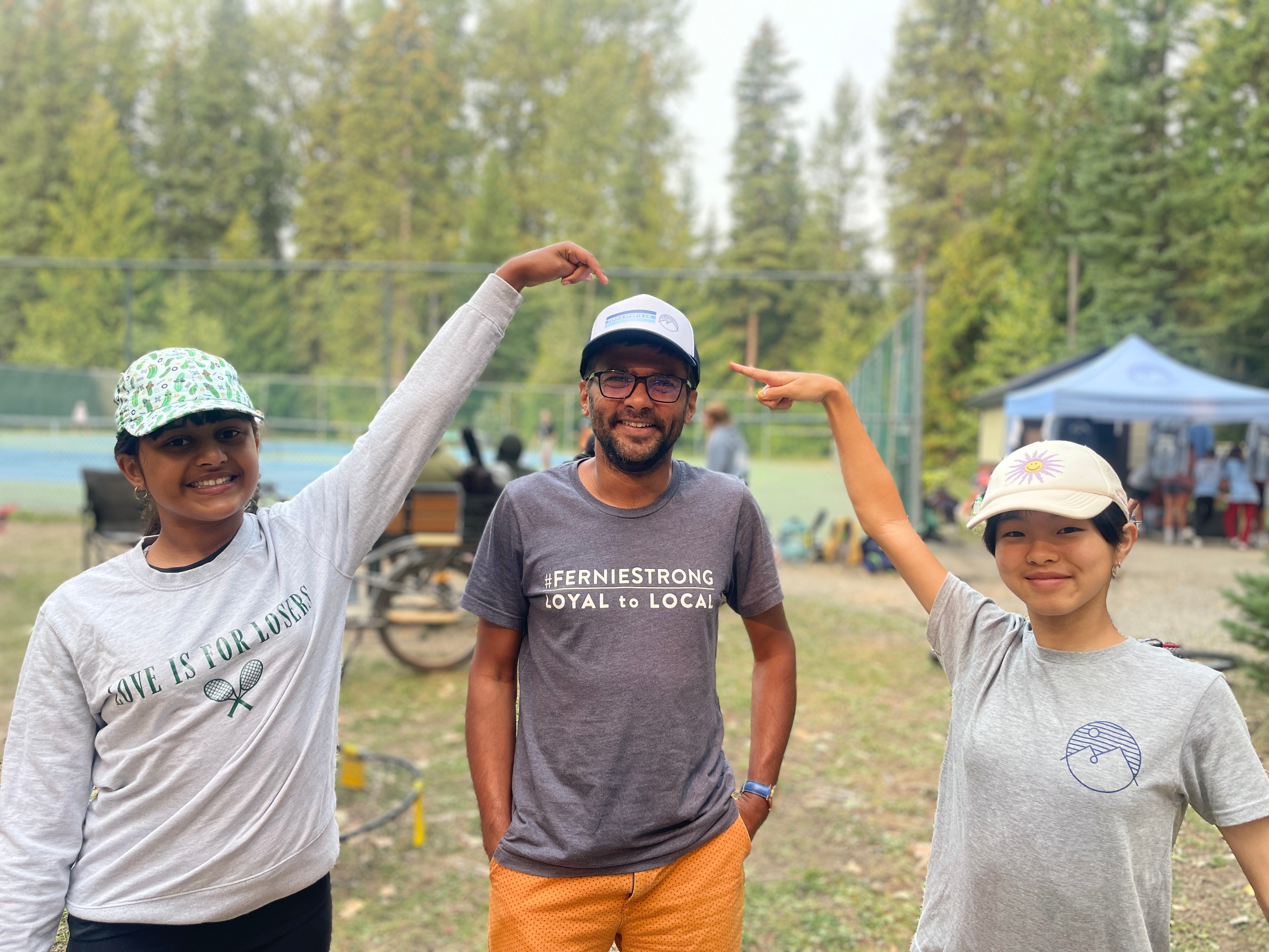 Harshan Ramadass with kids at a Fernie tennis court wearing a FernieStrong shirt